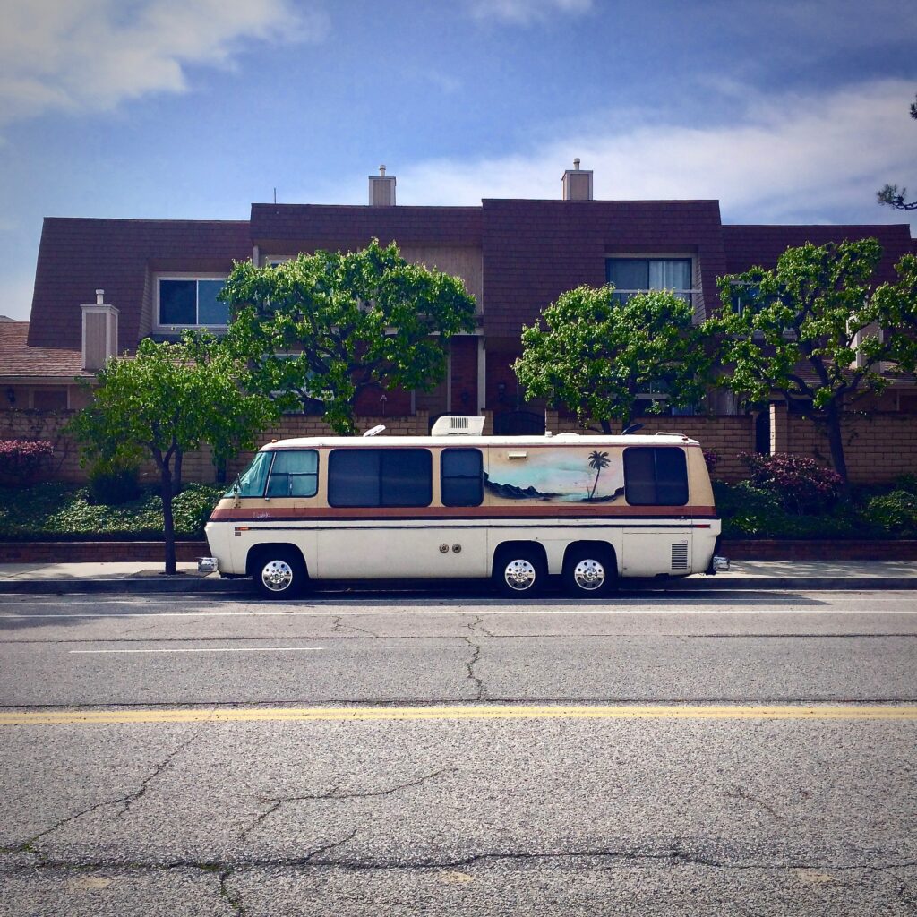 Old motor home parked on street with palm tree graphic on the side
